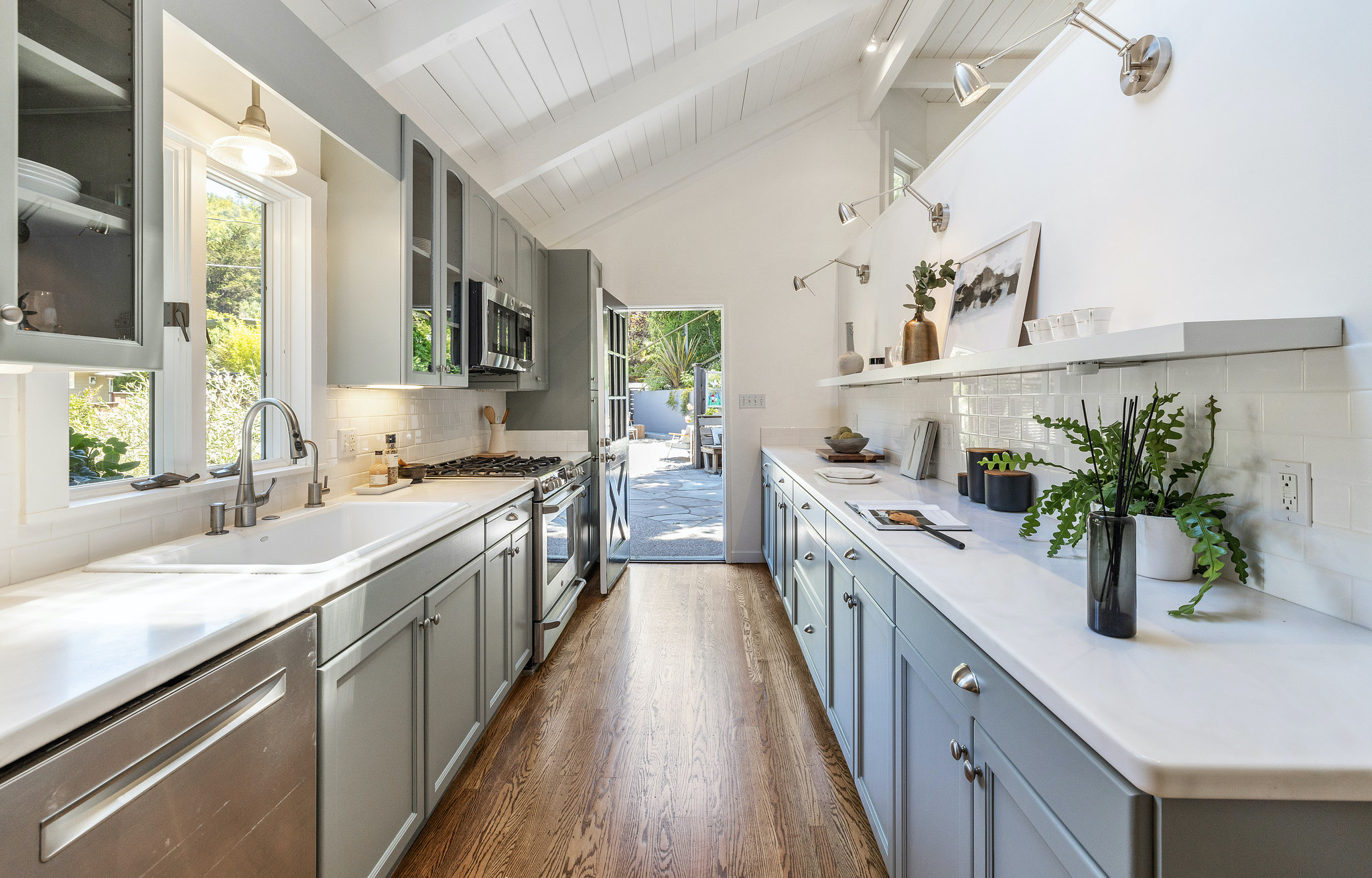 View of a galley-style kitchen with lux appliances and a door at one end