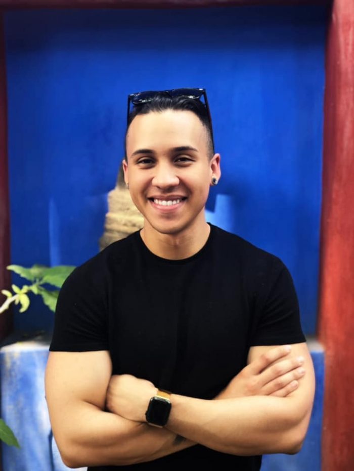 Young man in black shirt, in front of a blue wall