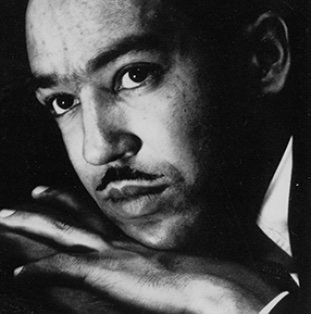 Close-up portrait of Langston Hughes, shown with his head resting on his hands