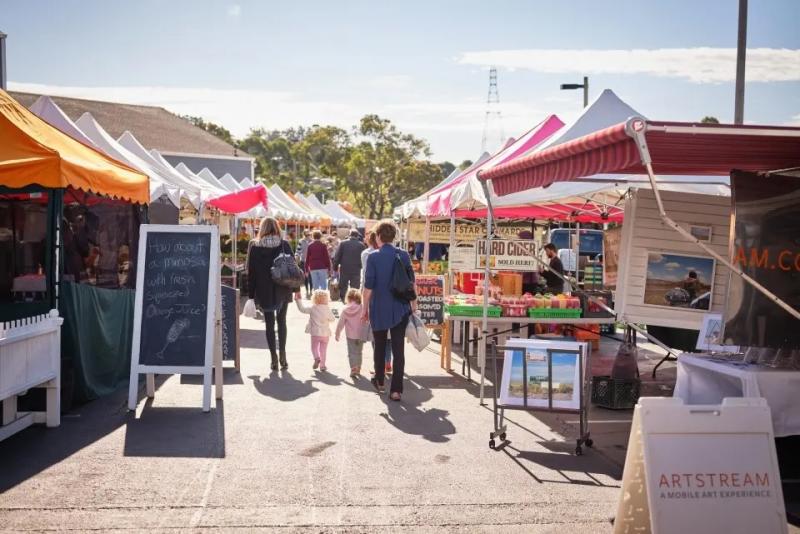 Street view of a farmers market showing people walking hand-in-hand
