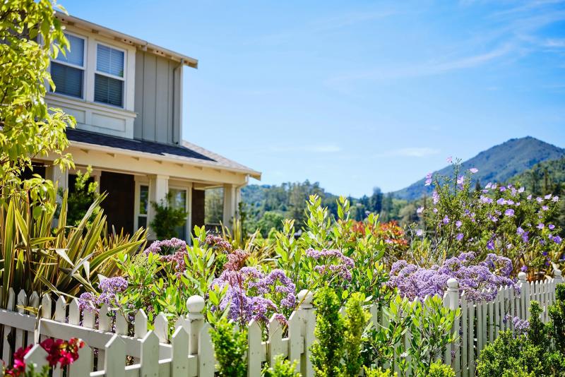 View of a home in Larkspur, showing a white picket fence and flowers